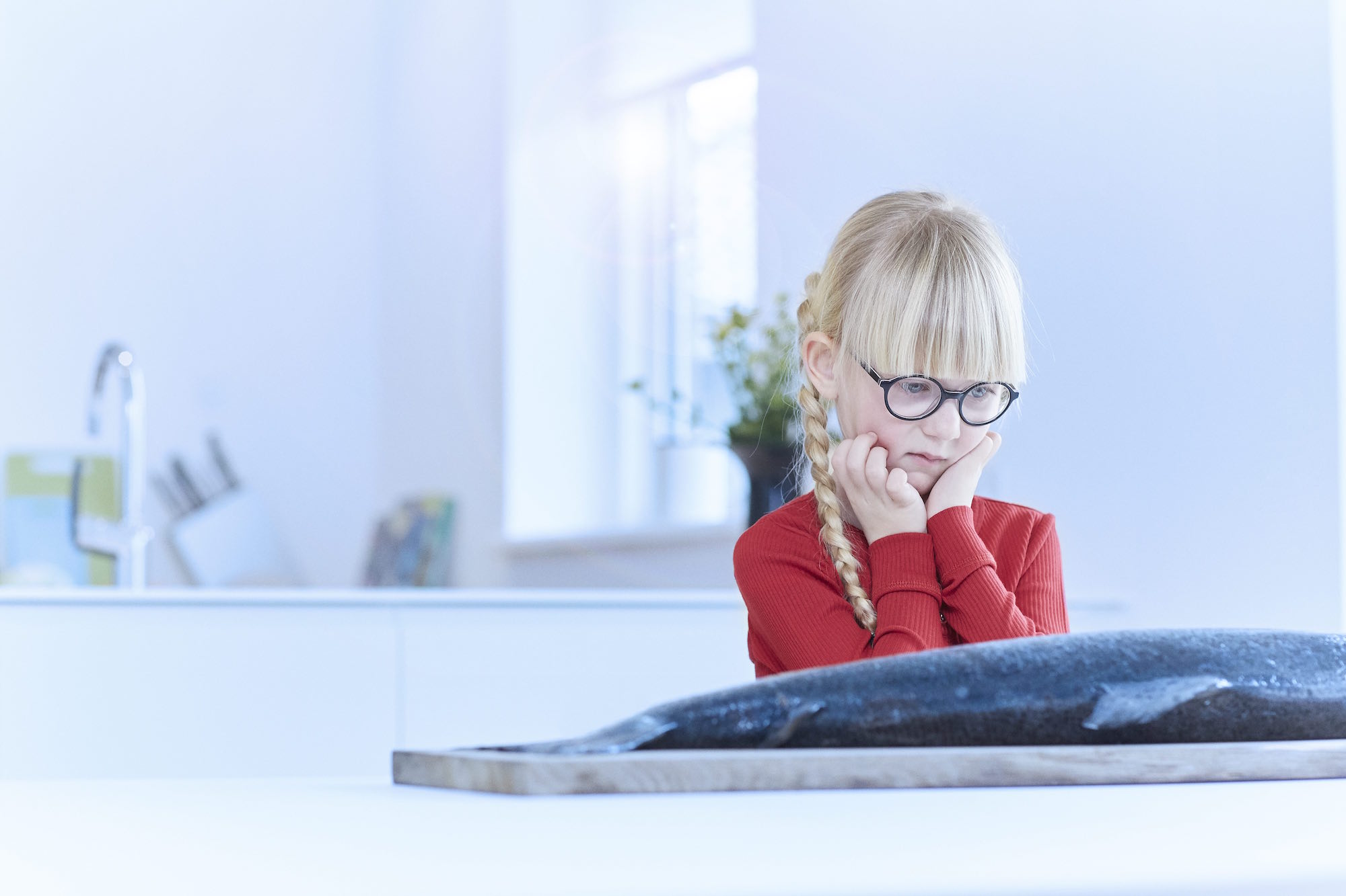 Pige med cerebral parese kigger undrende på laks, der ligger på bordet